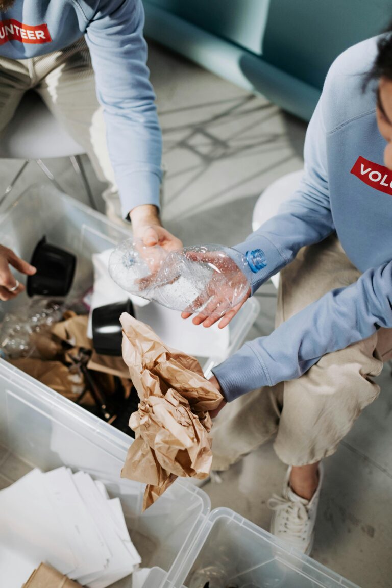 Volunteers in blue shirts sorting recyclable materials like paper and plastic.
