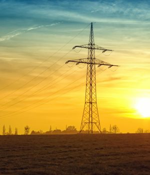 Silhouetted power lines stretch against a dramatic sunset sky, symbolizing energy and tranquility.